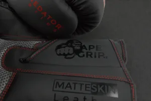 Close-up of ApeGrip V2 and MatteSkin branding on the Predator Series red accent boxing gloves.