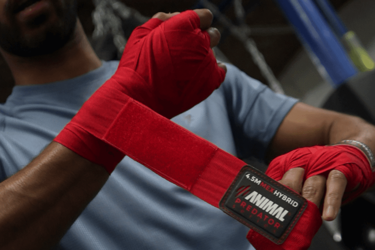 Boxer wrapping hands with red Mexican-style hand wraps before training.