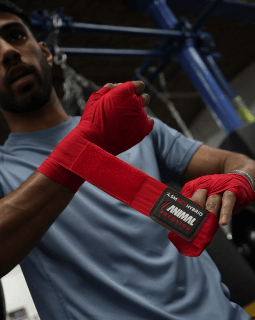 Boxer wrapping hands with red Mexican-style hand wraps before training.