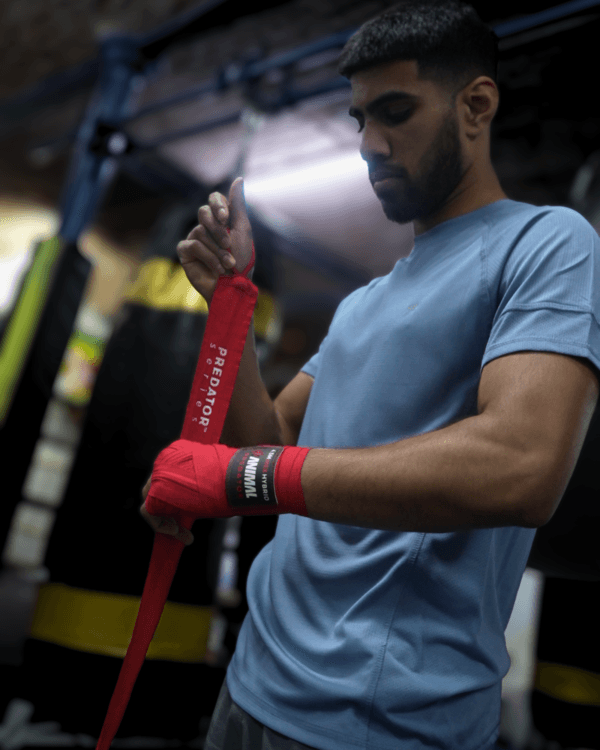 Boxer Moniah Miah wrapping hands with Animal Athletics Predator Series red hand wraps during training in a gym.