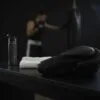 Predator Series black accent boxing glove on a gym bench with a boxer training in the background.
